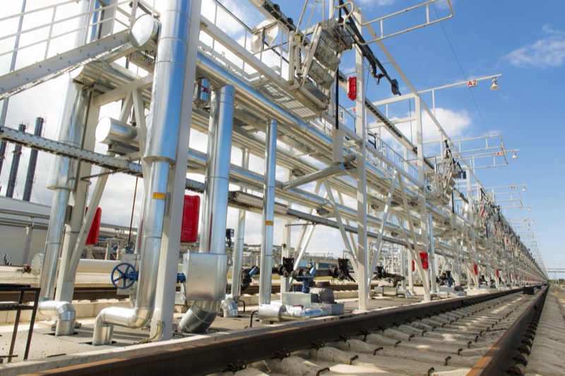 A rail unloading gantry with walkways and pipework runs alongside the track at Liwathon E.O.S.